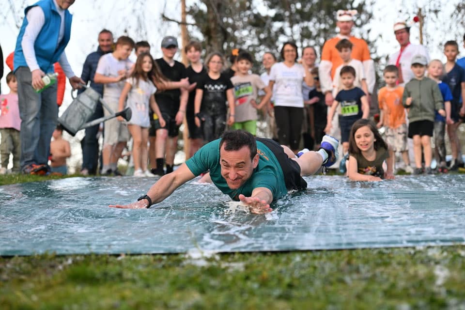 Glissade dans l'eau lors de la course enfants, grand moment de fête du cross